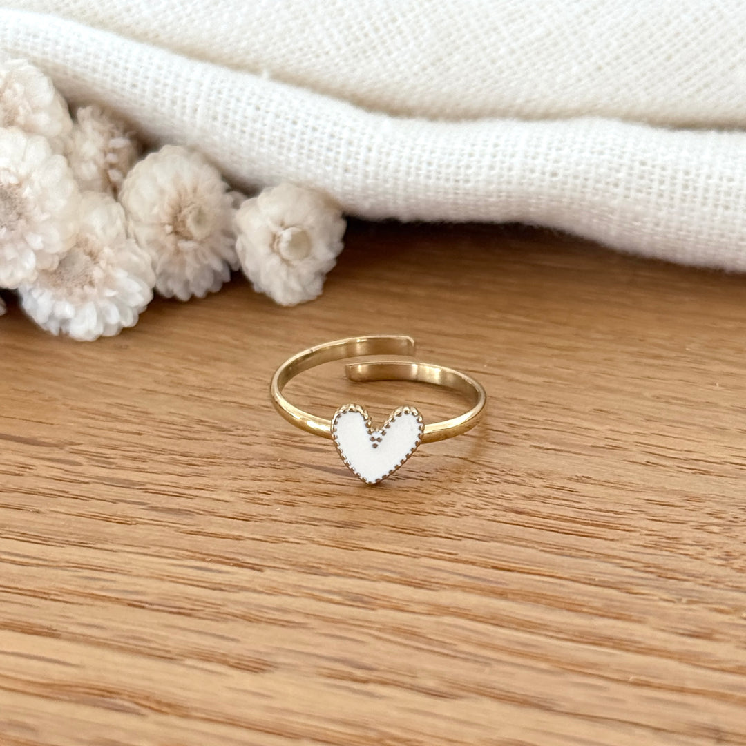 Bague ajustable dorée ornée d’un cœur blanc émaillé.