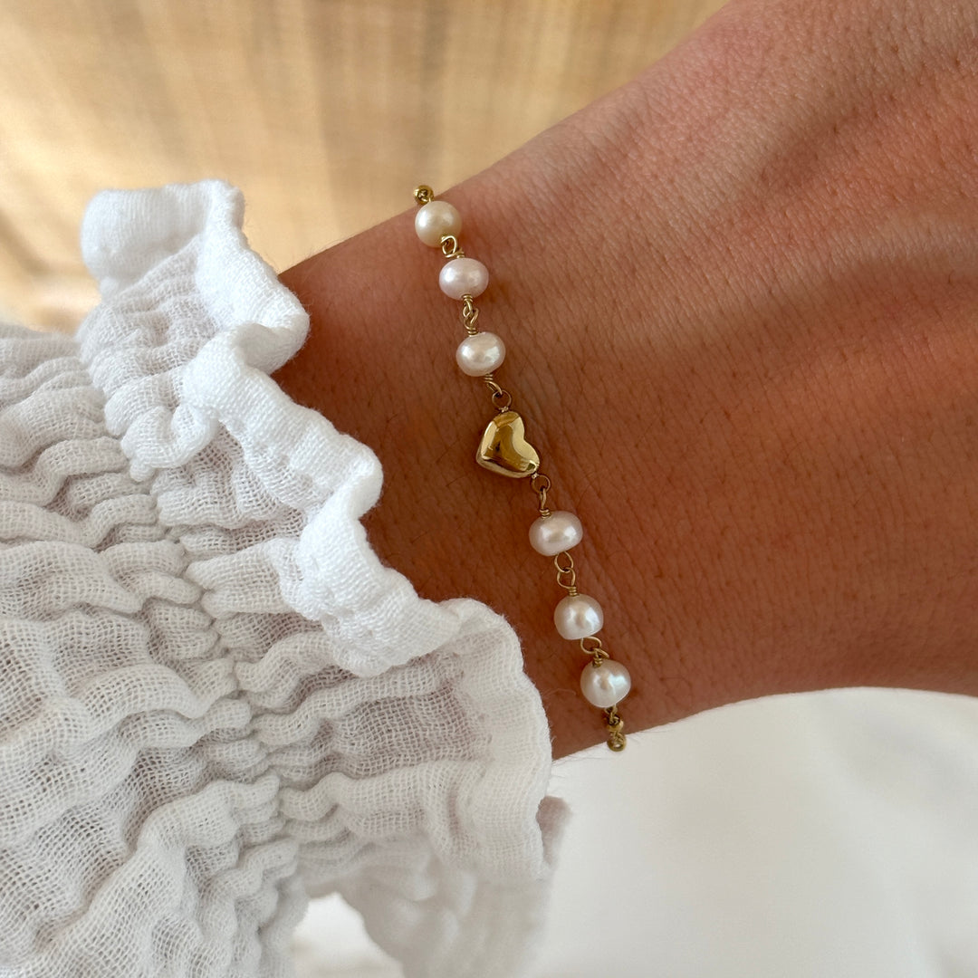 Bracelet en acier inoxydable orné de perles d’eau douce et d’un pendentif cœur central.