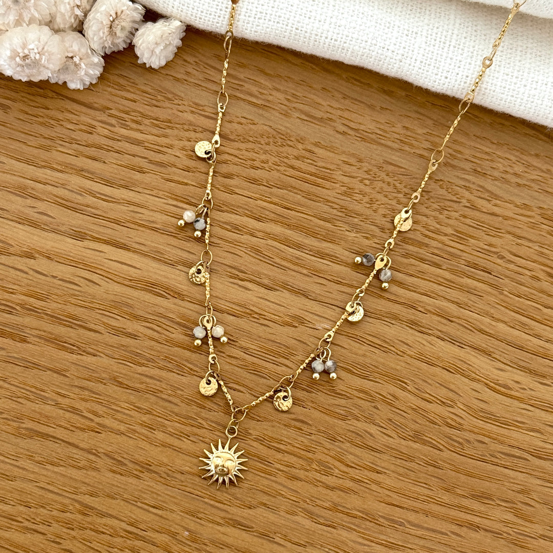 A necklace on a stainless steel chain featuring a sun pendant, hammered round discs, and natural stones.